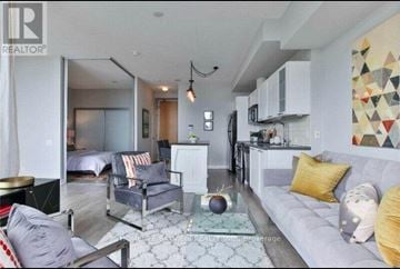 Toronto (Waterfront Communities) condo for rent - A modern living room with a grey couch and a glass coffee table.