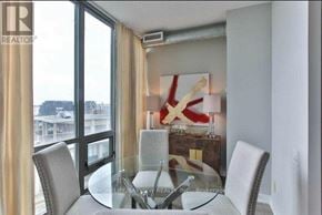 Toronto (Waterfront Communities) condo for rent - A dining room with a glass table and chairs, a large window with curtains, and a red and white abstract painting on the wall.