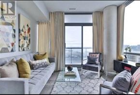 Toronto (Waterfront Communities) condo for rent - A living room with a grey sofa, a coffee table, and a view of the city.