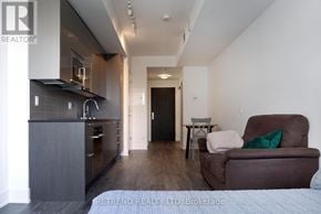 Toronto (Church-Yonge Corridor) condo for rent - A modern kitchen with dark wood floors and a brown recliner chair with a green pillow.