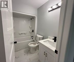 Windsor apartment for rent - A white bathroom with a toilet, sink, and shower.