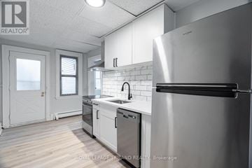 London South (South F) multi-family for rent - A modern kitchen with a stainless steel refrigerator and white cabinets.