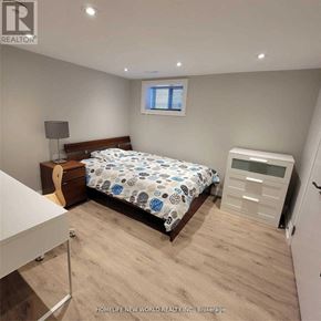 Toronto (Englemount-Lawrence) apartment for rent - A bedroom with a bed, nightstand, and a small white cabinet.