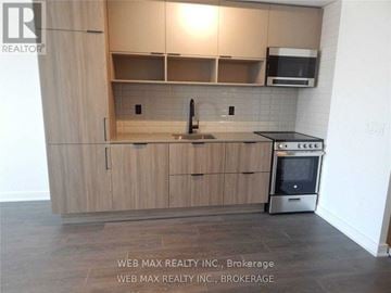 Toronto (Waterfront Communities) condo for rent - A kitchen with wooden cabinets and a black stove top oven.