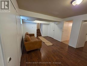 Brampton (Madoc) apartment for rent - A living room with a brown couch and a staircase in the background.