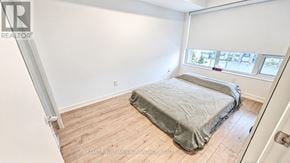 Toronto (Weston) condo for rent - A bedroom with a bed covered in a grey sheet.