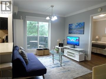 Hamilton condo for rent - A living room with a blue couch and a television on a white stand.