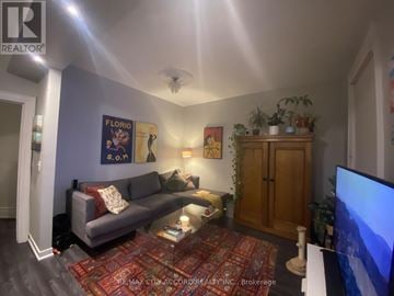 Toronto (Little Portugal) fourplex for rent - A living room with a grey couch and a red rug.