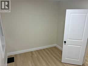 Hamilton apartment for rent - A white door is on the right side of a room with light colored walls and a wooden floor.