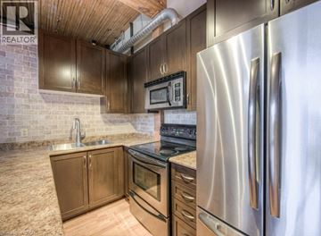 Kitchener condo for rent - A kitchen with a stainless steel refrigerator and wooden cabinets.