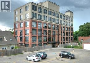 Kitchener condo for rent - A multi-story building with a parking lot in front.