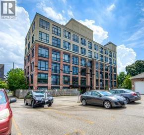 Kitchener condo for rent - A parking lot with cars and a building with the logo REALTOR.