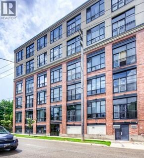 Kitchener condo for rent - A tall building with many windows and a car parked in front.