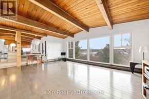 Parry Sound apartment for rent - A spacious room with wooden ceiling and floor, furnished with a dining table and chairs, and a large window with a view of trees outside.
