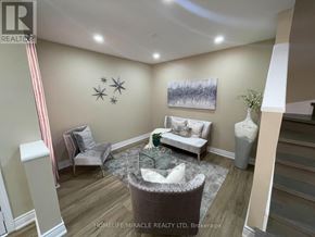 Brampton (Fletcher's Meadow) apartment for rent - A living room with a grey sofa, a white armchair, a glass coffee table, and a painting on the wall.