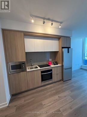 Mississauga (City Centre) condo for rent - A modern kitchen with wooden cabinets and stainless steel appliances.