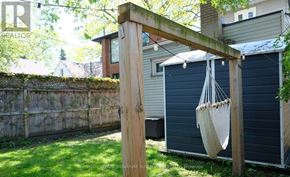 Toronto (Woodbine-Lumsden) apartment for rent - A wooden pergola with a hanging planter is in the foreground of a backyard.