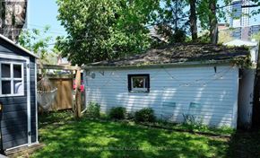Toronto (Woodbine-Lumsden) apartment for rent - A small white shed with a window and a door is surrounded by a green lawn.