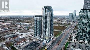 Vaughan (Vaughan Corporate Centre) condo for rent - A tall building with a glass facade stands in the middle of a cityscape.