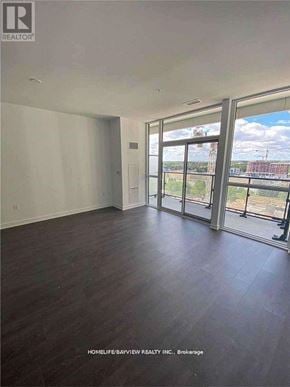Richmond Hill (Langstaff) condo for rent - A spacious room with wooden floors and large windows overlooking a cityscape.