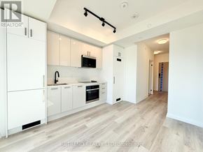 Toronto (Kensington-Chinatown) condo for rent - A modern kitchen with white cabinets and a wooden floor.