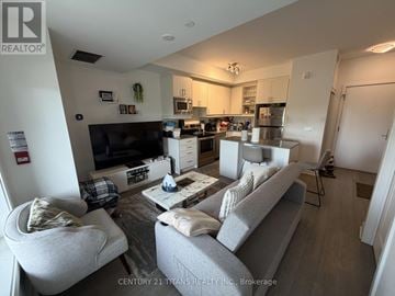 Toronto (Downsview-Roding-Cfb) townhouse for rent - A living room with a grey couch and a white chair.