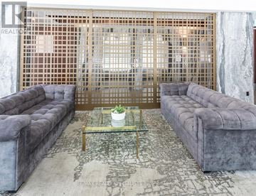 Toronto (Niagara) condo for rent - A living room with a grey couch and a glass coffee table.