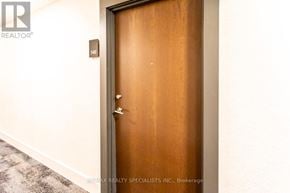 Toronto (Niagara) condo for rent - A brown door with a silver handle is in a room with a grey carpet.