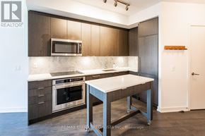 Toronto (Niagara) condo for rent - A kitchen with a table and a microwave above it.