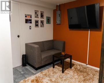 London East (East L) apartment for rent - A living room with a grey couch and a flat screen TV mounted on the wall.
