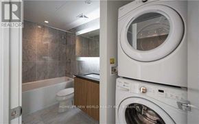 Toronto (Waterfront Communities) condo for rent - A washing machine is placed in a room with a tiled wall.