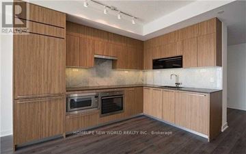 Toronto (Waterfront Communities) condo for rent - A modern kitchen with wooden cabinets and a stainless steel range hood.