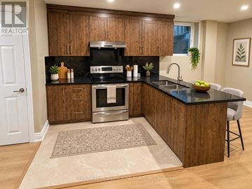 Guelph (Kortright West) apartment for rent - A modern kitchen with wooden cabinets and a black countertop.