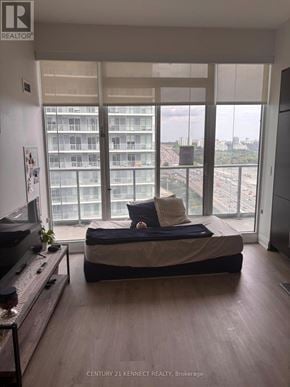 Toronto (Bayview Village) condo for rent - A bedroom with a bed, a television, and a window overlooking a cityscape.
