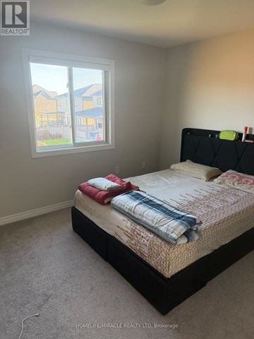Thorold (Rolling Meadows) apartment for rent - A bedroom with a large bed and a window overlooking a residential area.