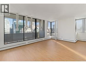 Vancouver apartment for rent - A large empty room with wooden floors and a view of the city through the windows.
