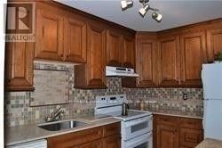Brampton (Madoc) townhouse for rent - A kitchen with wooden cabinets and a white stove top oven.