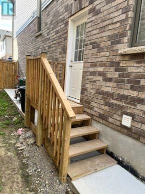 North Dumfries apartment for rent - A wooden staircase with a white door and a brick wall.