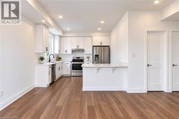 Hamilton townhouse for rent - A modern kitchen with white cabinets and wooden floors.