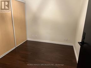 Toronto (Niagara) condo for rent - A room with a wooden floor and a white wall with a black door on the right side.