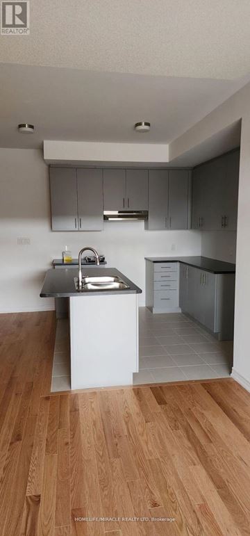 Oshawa (Kedron) townhouse for rent - A kitchen with a black countertop and wooden flooring.