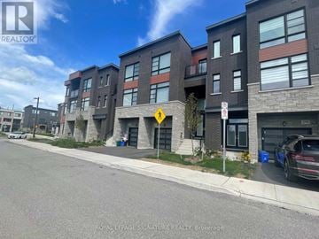 Vaughan (Kleinburg) townhouse for rent - A street view of a residential area with apartment buildings and a car parked on the side of the road.