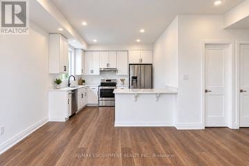Hamilton (Kirkendall) townhouse for rent - A modern kitchen with white cabinets and a wooden floor.