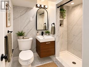Niagara Falls (Brown) apartment for rent - A bathroom with a white toilet and a marble wall.