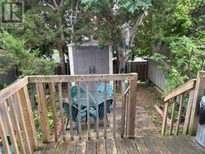 Ottawa townhouse for rent - A wooden deck with a table and chairs is surrounded by greenery.