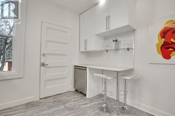 Ottawa triplex for rent - A white kitchen with a bar stool and a painting on the wall.