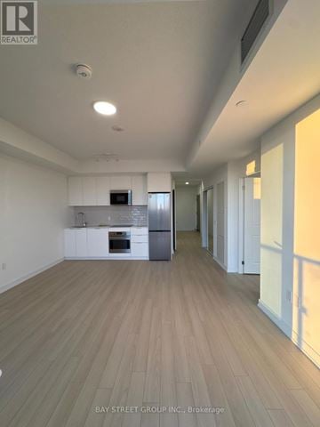Brampton (Bram East) condo for rent - A spacious kitchen with white cabinets and a wooden floor.