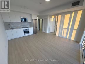Brampton (Bram East) condo for rent - A spacious kitchen with white cabinets and a wooden floor.