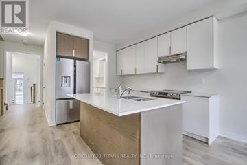 Pickering townhouse for rent - A modern kitchen with white cabinets and a wooden island.