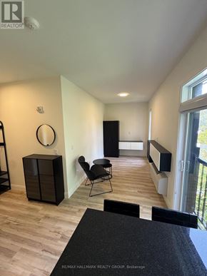 Ottawa multi-family for rent - A black chair is in a white room with wood flooring.